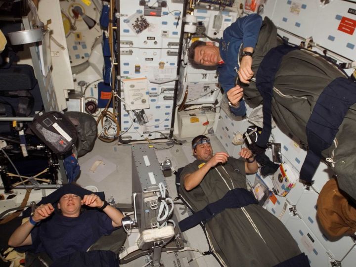 Astronaut sleeping in space capsule