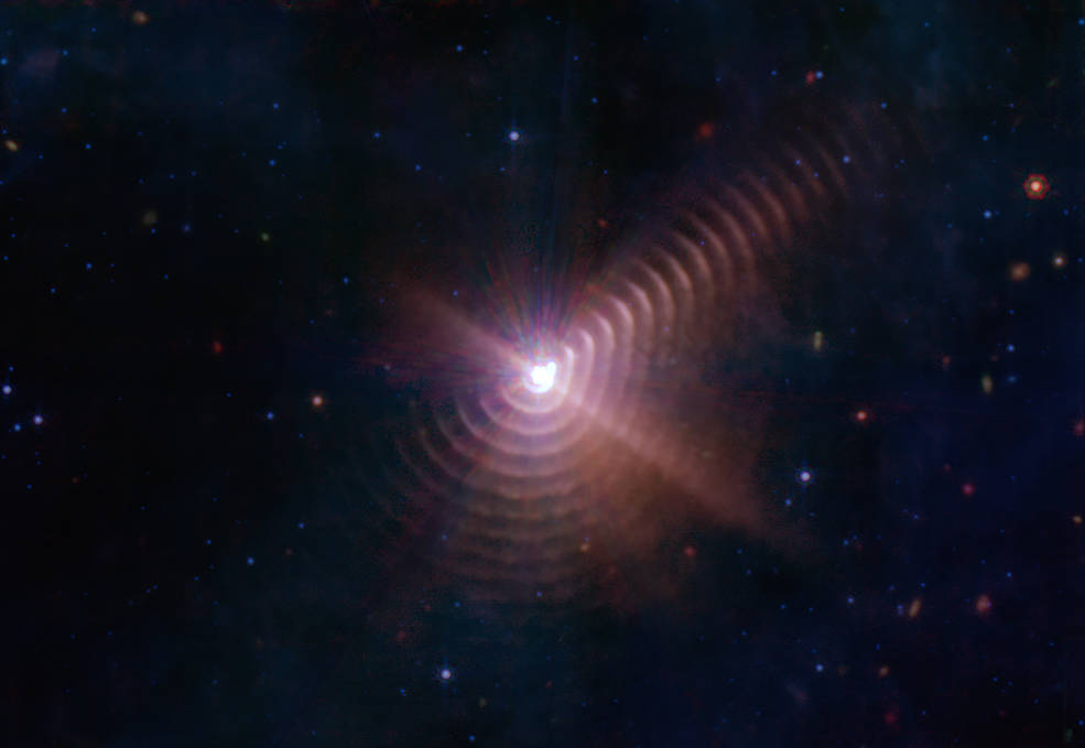 The two stars in Wolf-Rayet 140 produce shells of dust every eight years that look like rings, as seen in this image from NASA’s James Webb Space Telescope. Each ring was created when the stars came close together and their stellar winds collided, compressing the gas and forming dust. Credits: NASA, ESA, CSA, STScI, JPL-Caltech
